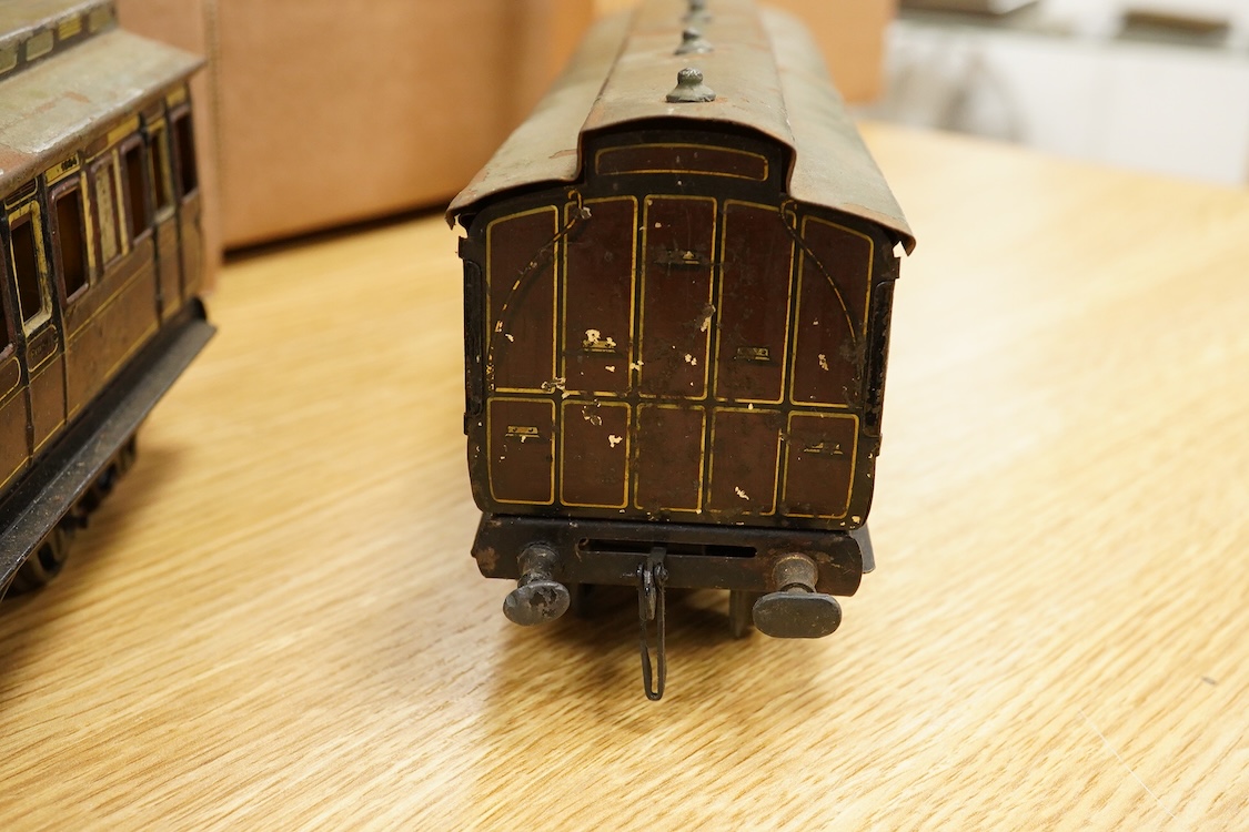 Three Carette for Bassett-Lowke 0 gauge tinplate GWR clerestory bogie coaches; two First Third Composite coaches, both 1324, and a full brake van, 1334, all in chocolate and cream livery